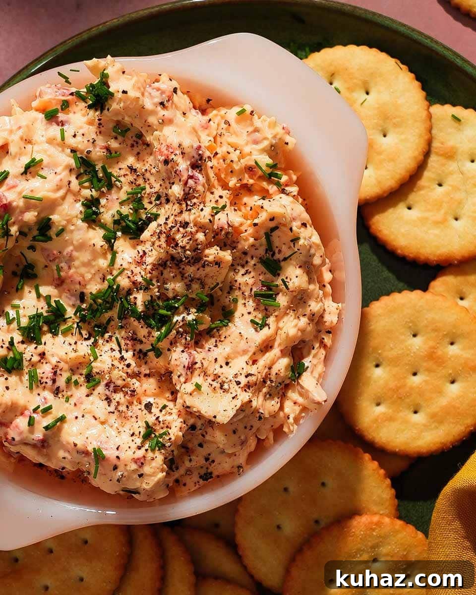 14 Crowd-Pleasing Game Day Appetizers 7 Cheddar pimento cheese dip garnished with chives, surrounded by round crackers.