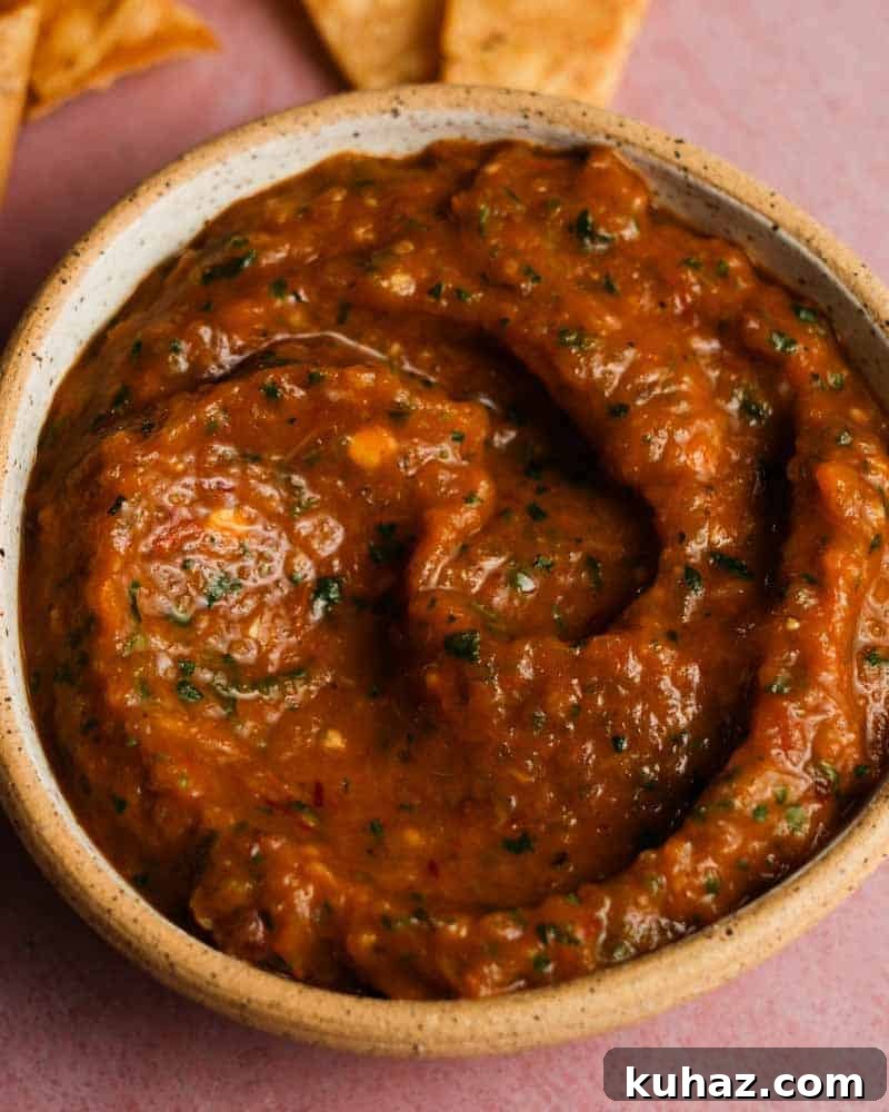 14 Crowd-Pleasing Game Day Appetizers 9 A bowl of roasted chipotle salsa with herbs, beside tortilla chips.