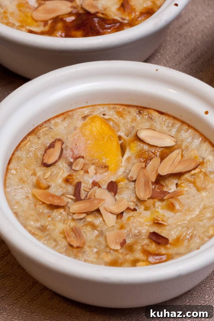 Peaches and Cream Baked Oatmeal Recipe 3 a small ramekin filled with peaches and oatmeal topped with slivered almonds.