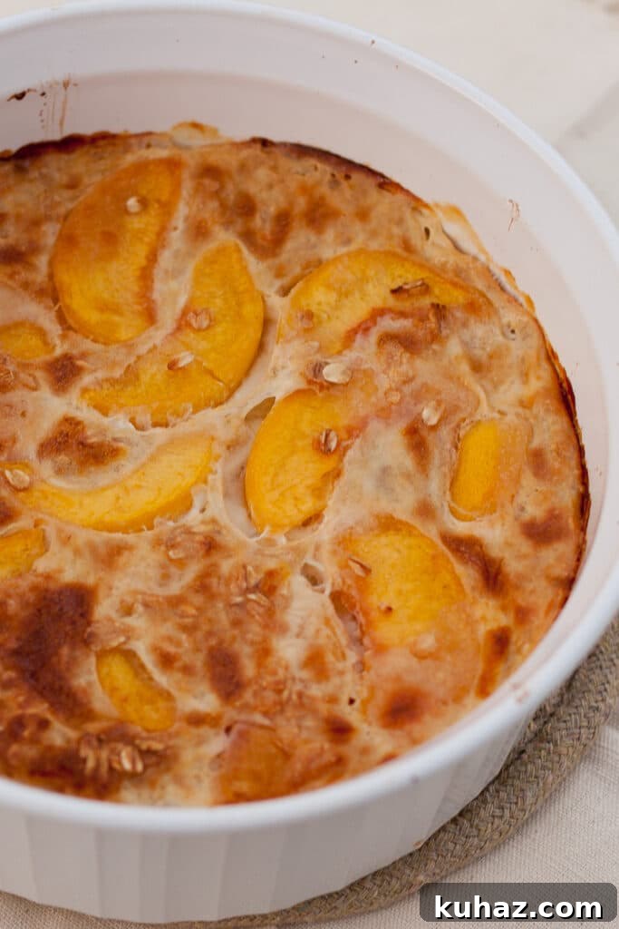 Peaches and Cream Baked Oatmeal Recipe 4 a large casserole dish filled with baked oatmeal with peaches in it.