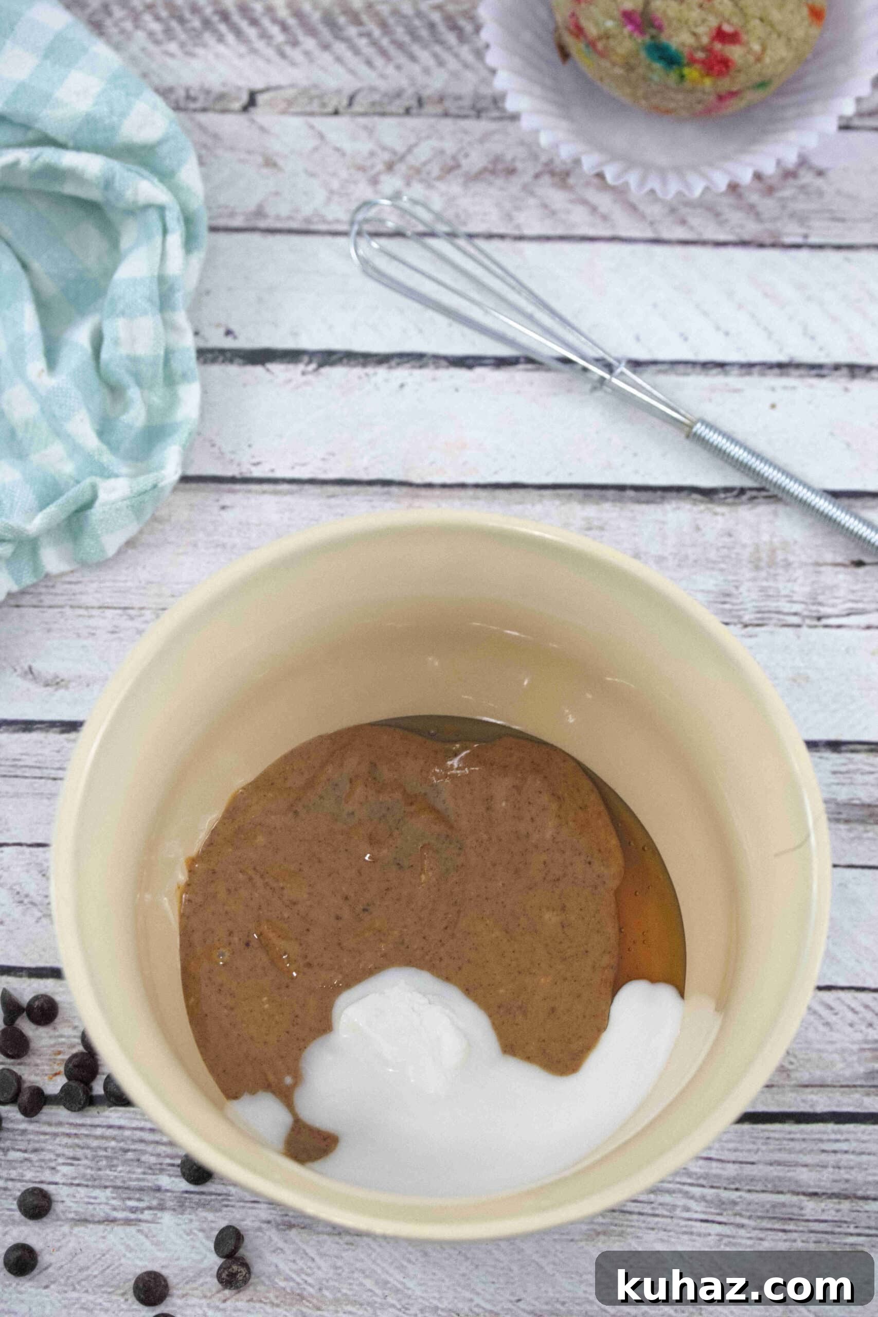 Bowl with nut butter and coconut cream and a whisk behind it.