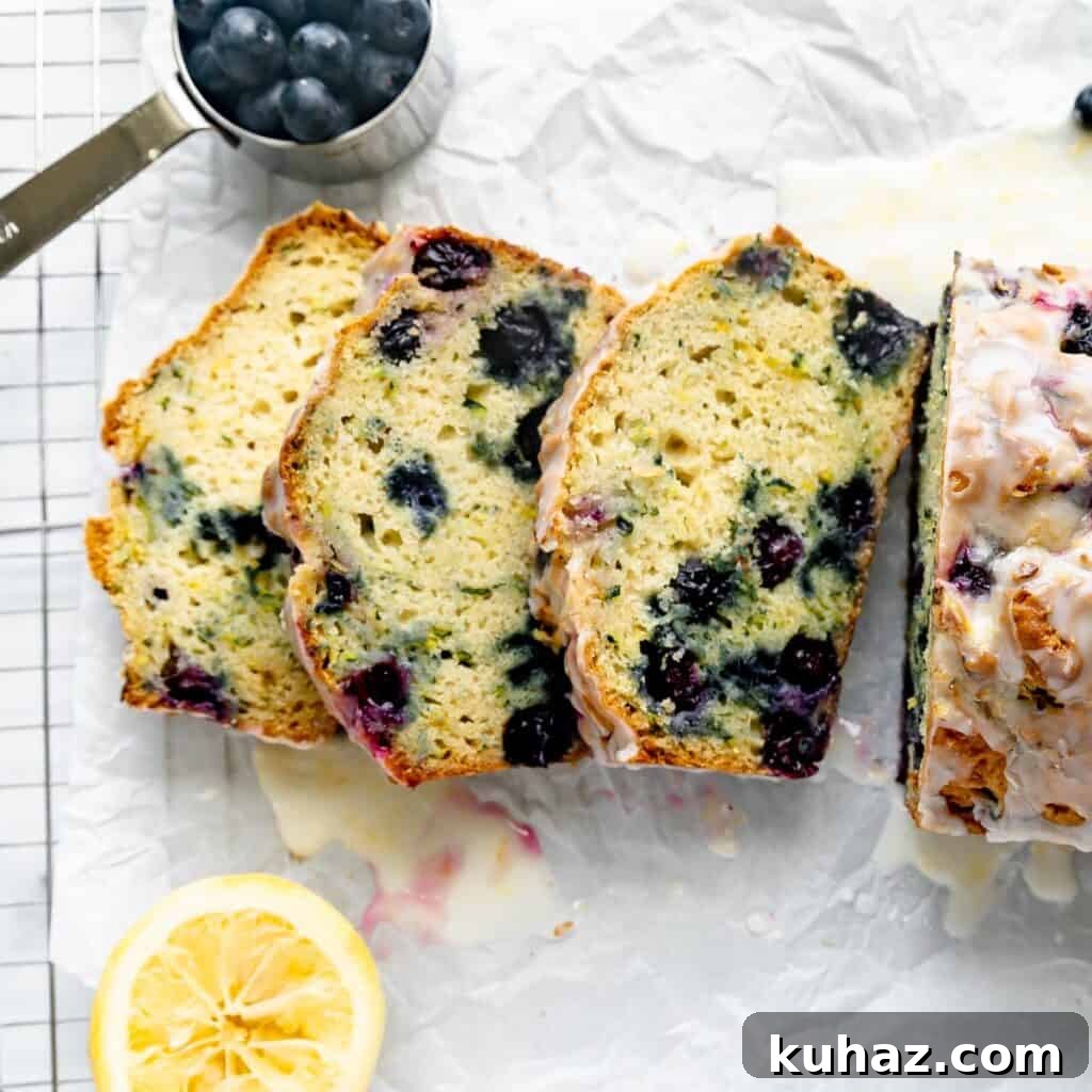 Three slices of zucchini bread with blueberries on white parchment paper.
