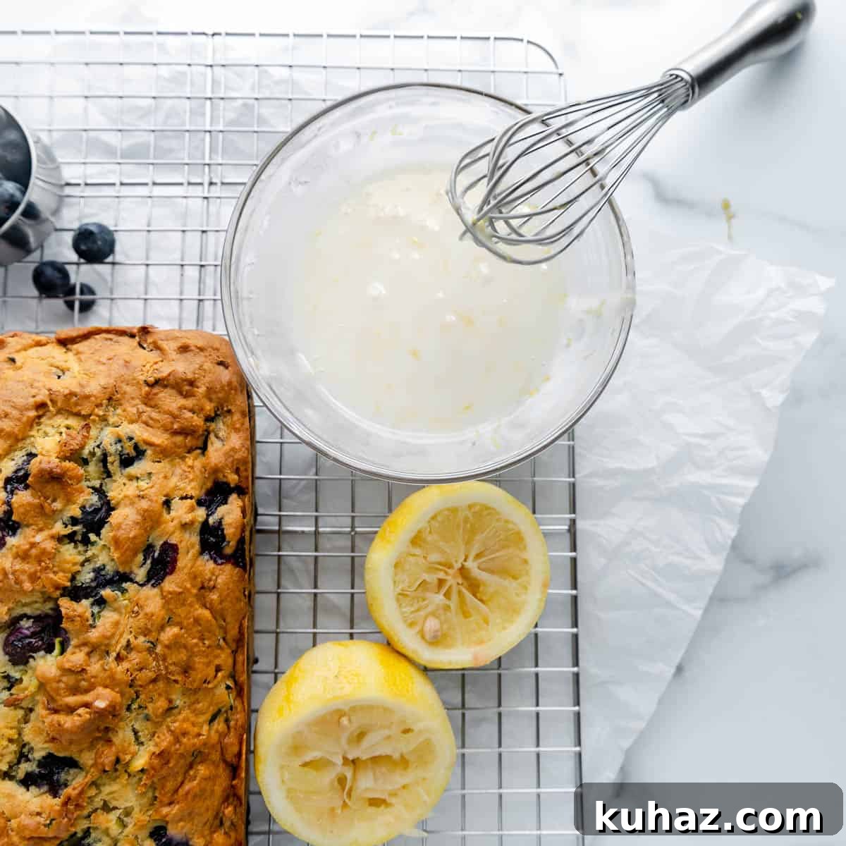 Glaze in a mixing bowl with whisk and bread and lemon on the side.