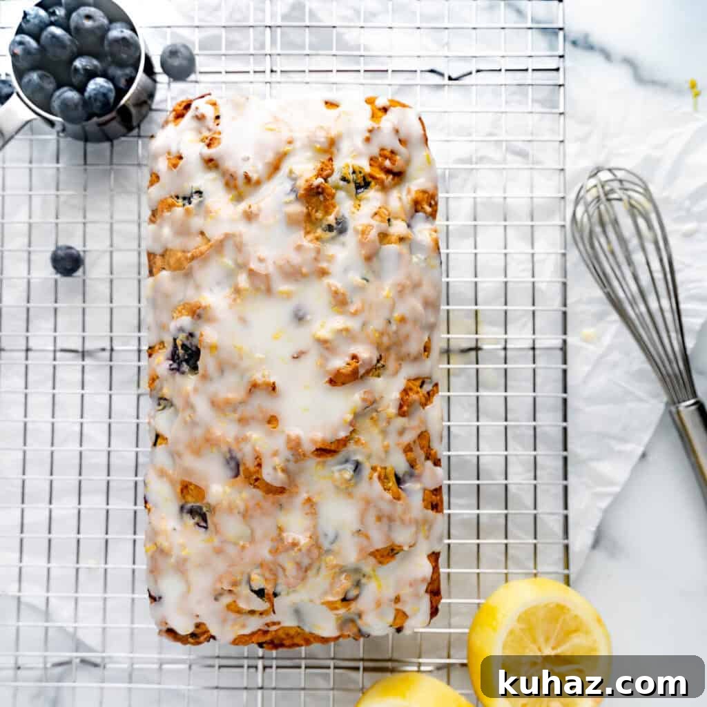 Glazed bread on a cooling rack with lemon and blueberries.