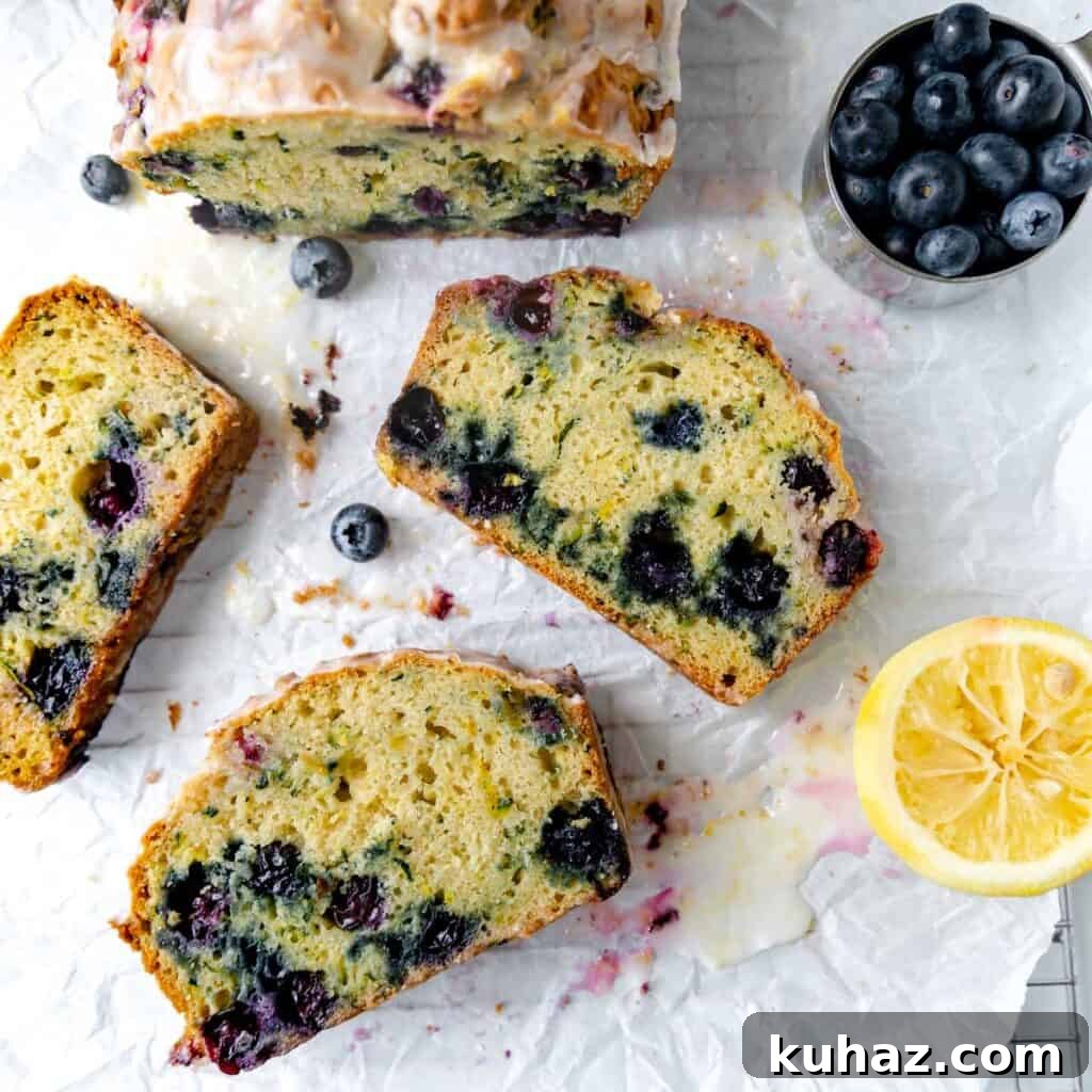 Sliced blueberry bread on parchment paper with lemon and blueberries.