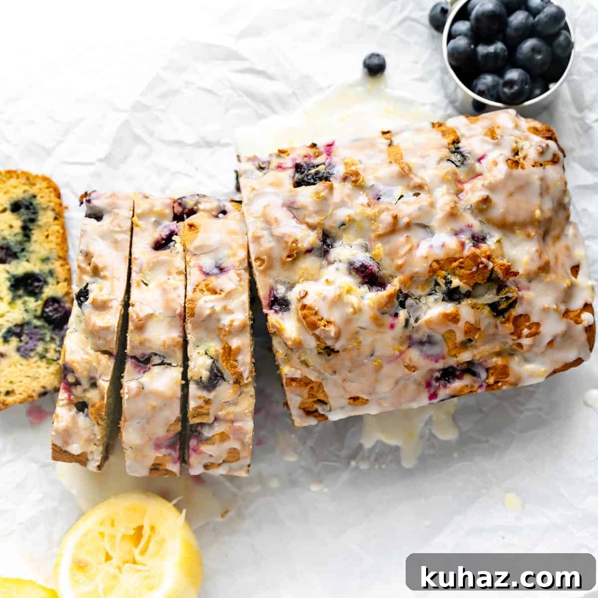 Overhead image of sliced bread on parchment paper. Lemon and blueberries around it.