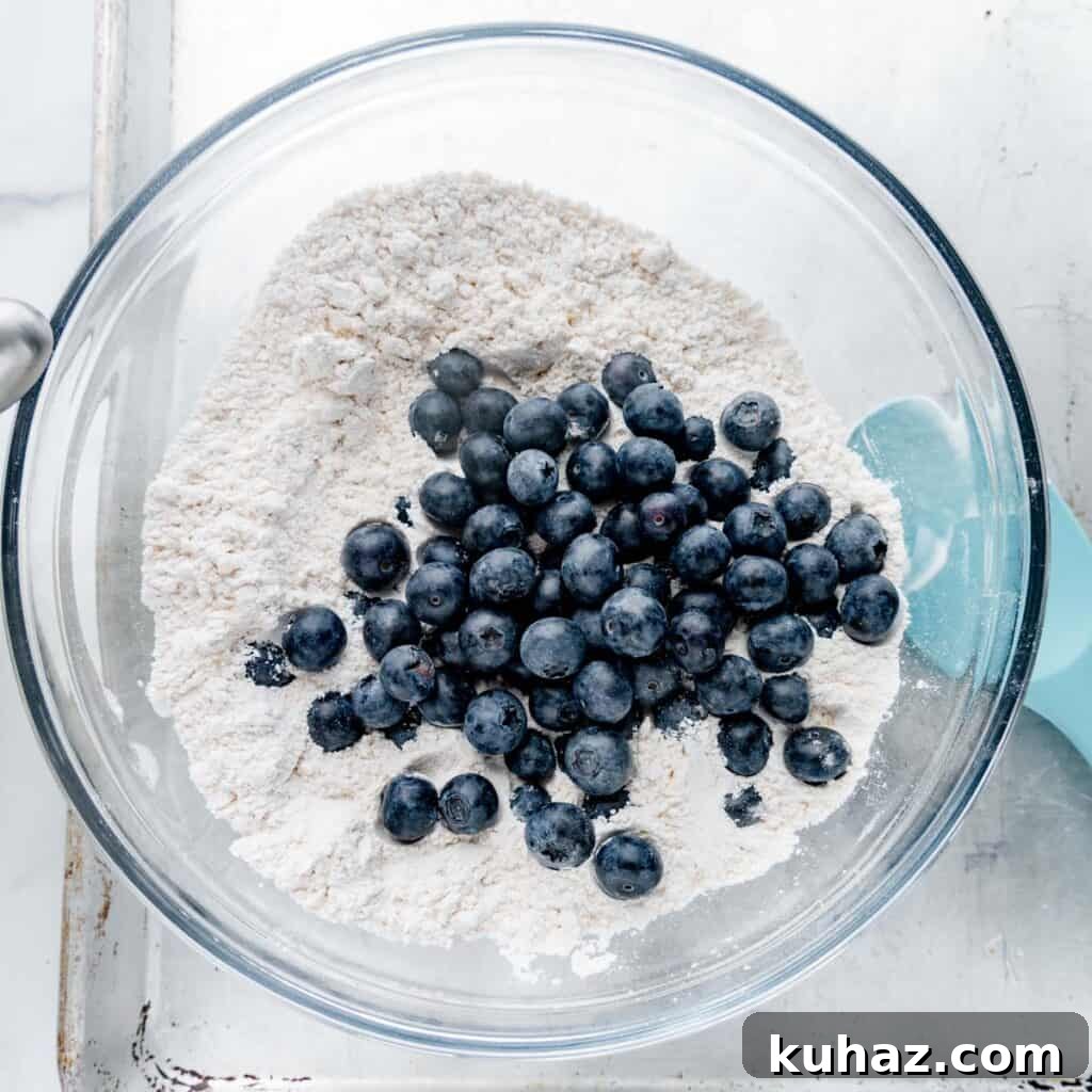 Blueberries added to flour in a mixing bowl.