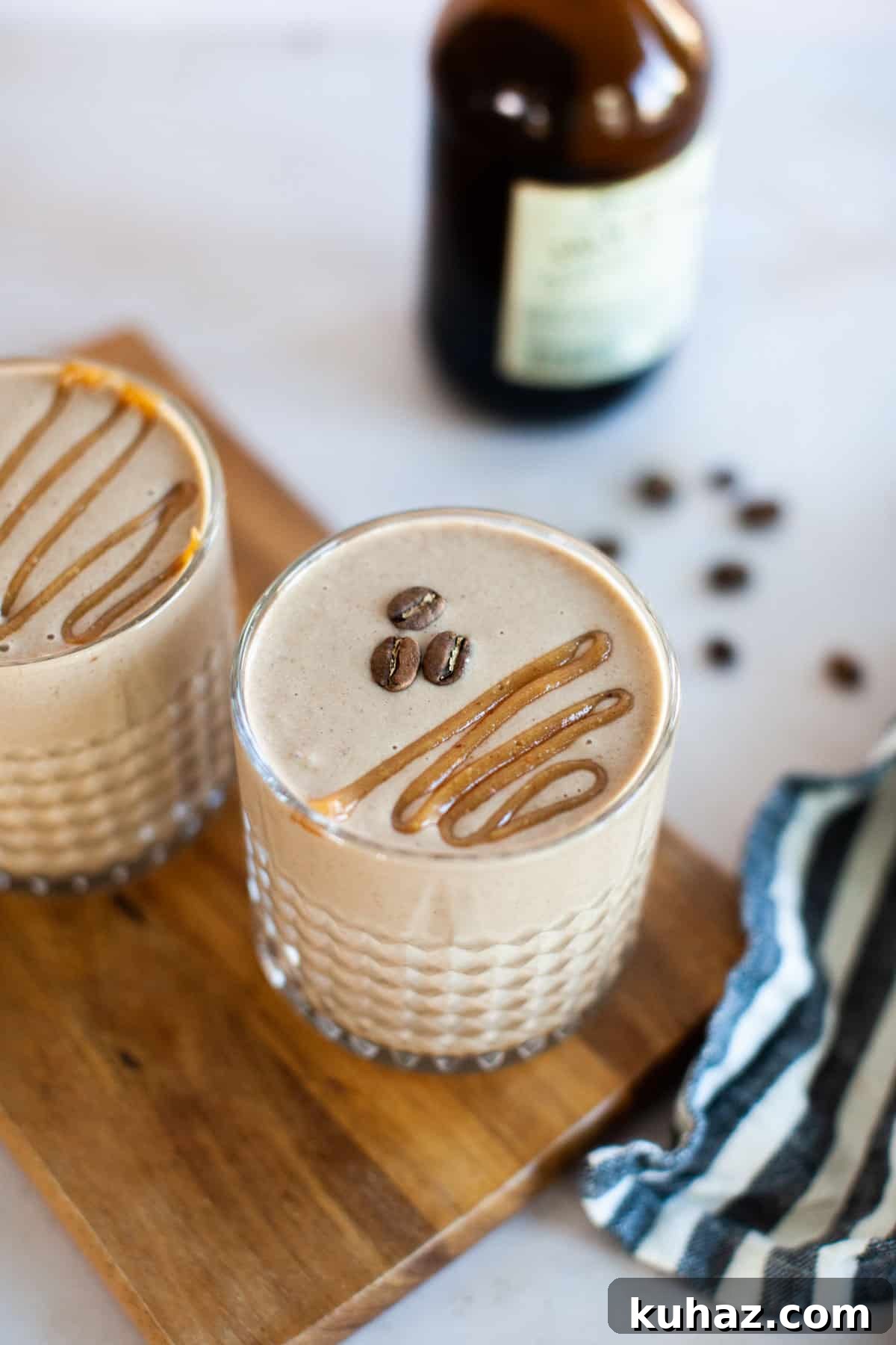 A close-up shot of two coffee smoothies topped with peanut butter drizzle and coffee beans.