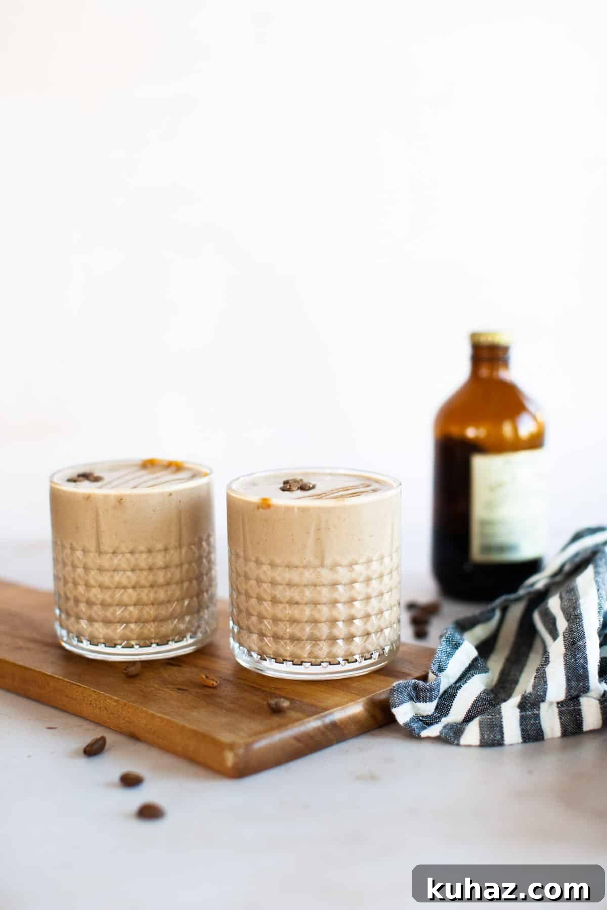 Two coffee smoothies sitting on a wooden cutting board.