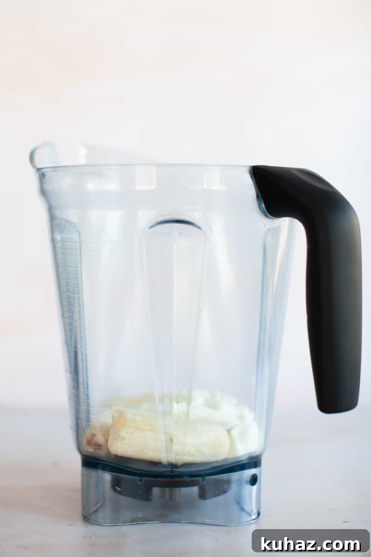 Frozen banana and plain Greek yogurt in a blender pitcher.