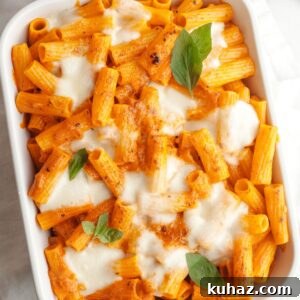 Baked vodka pasta in a white dish topped with basil leaves.