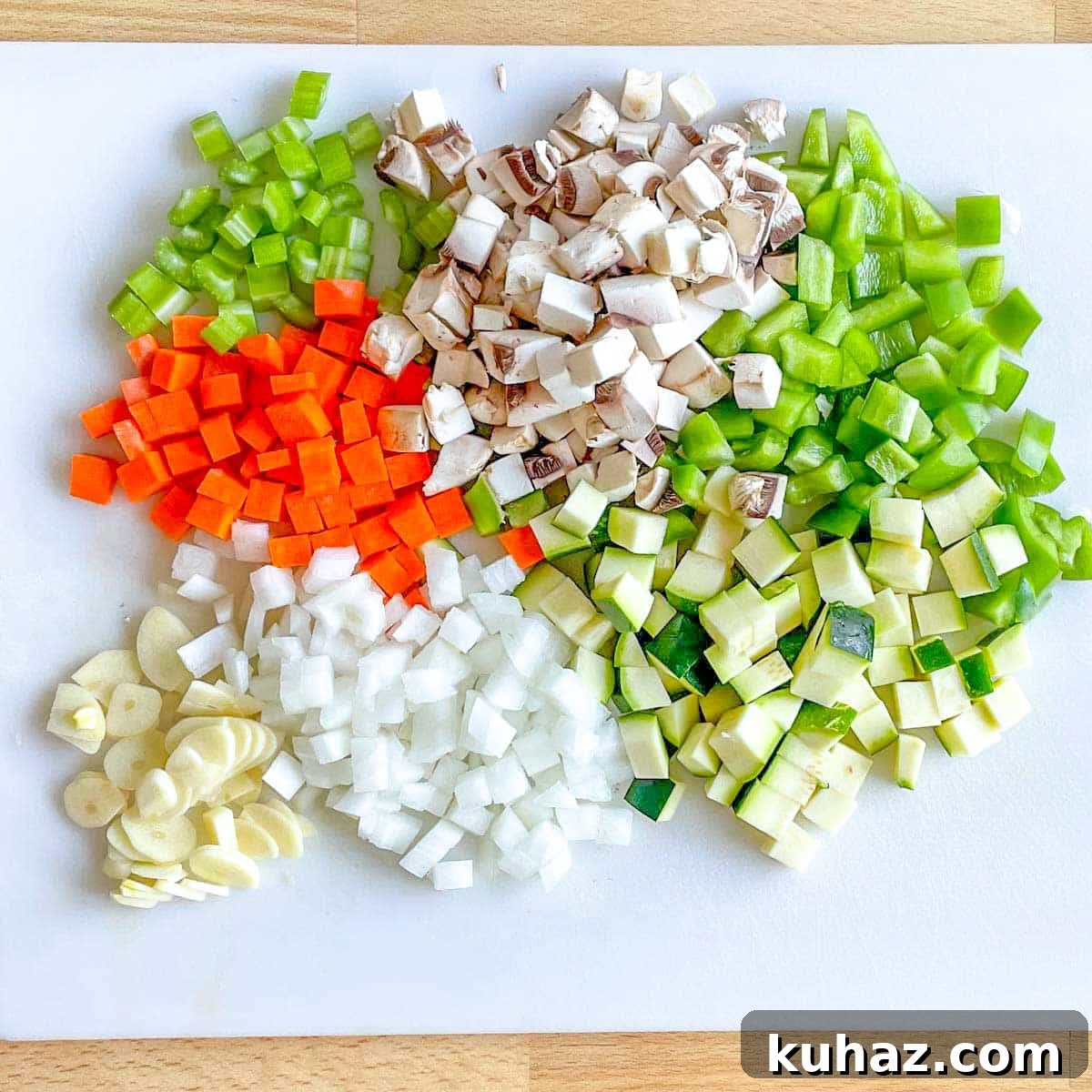 Linguine with Classic Bolognese Sauce 3 Diced carrot, celery, mushrooms, green bell pepper, zucchini, onion, and sliced garlic sit on a white cutting board.