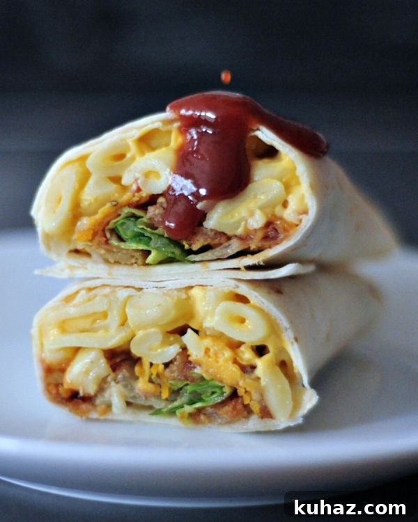 A BBQ mac and cheese burrito sliced in half on a white plate, with BBQ sauce dripping on top.