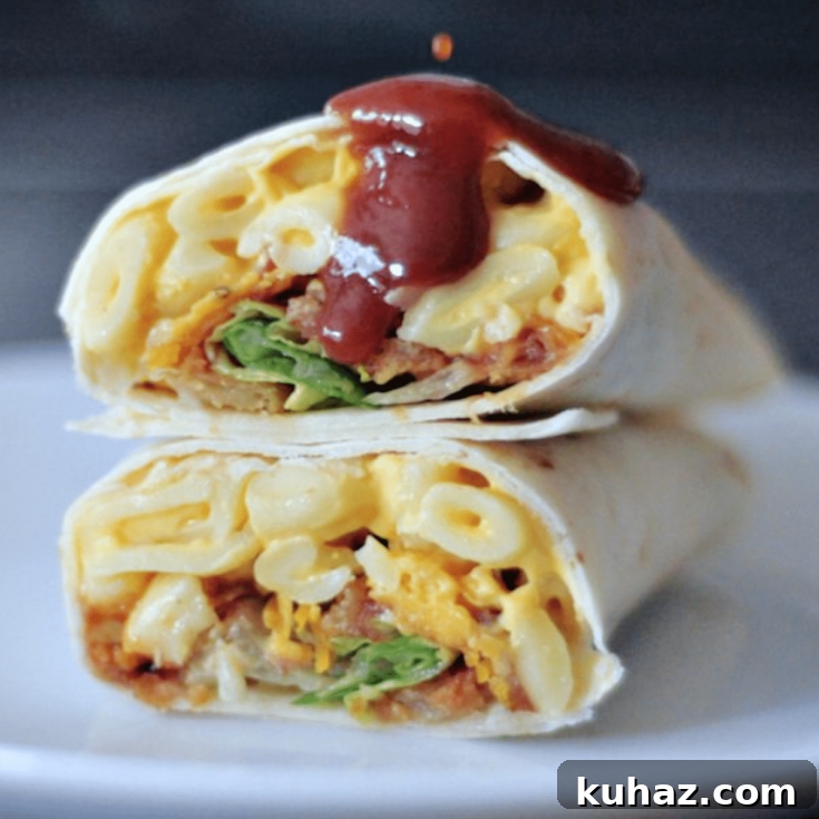 A BBQ mac and cheese burrito sliced in half on a white plate, with BBQ sauce dripping on top.