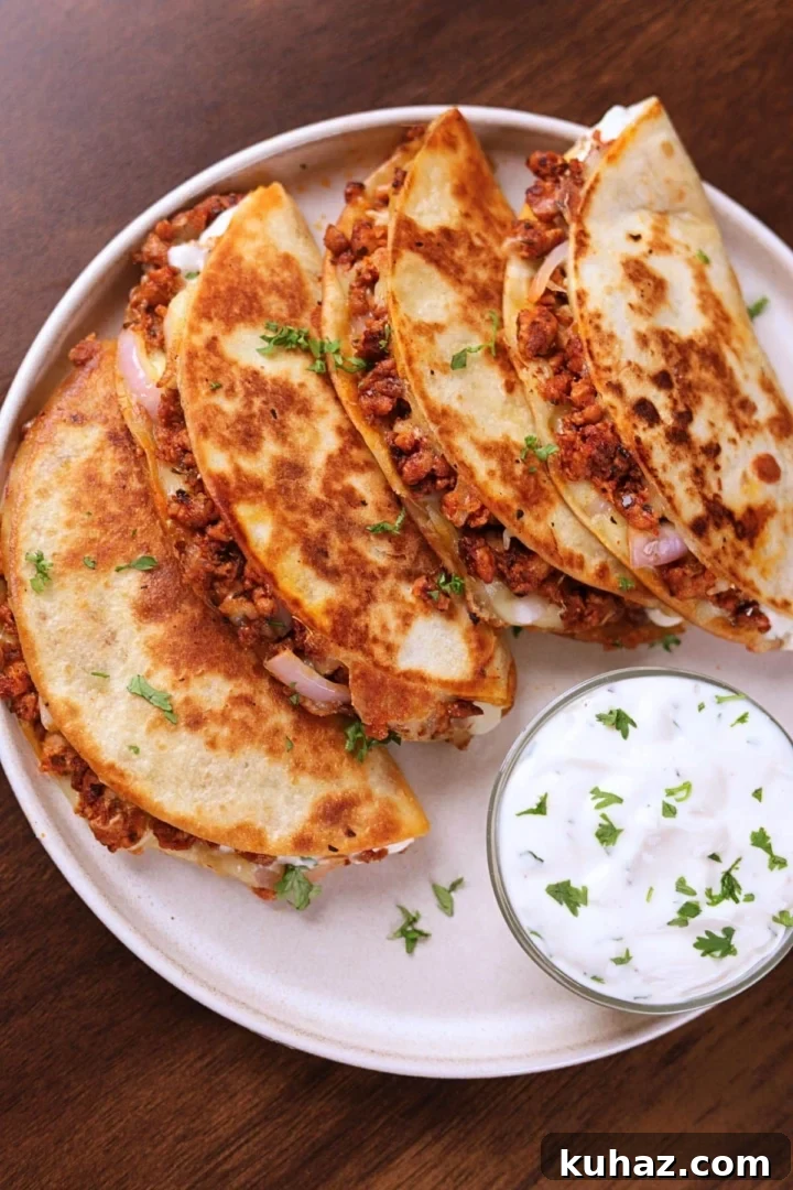 Crispy Ground Chicken Tacos with Crunchy Shells 2 Crispy ground chicken tacos served on a white plate with creamy garlic sauce on the side.