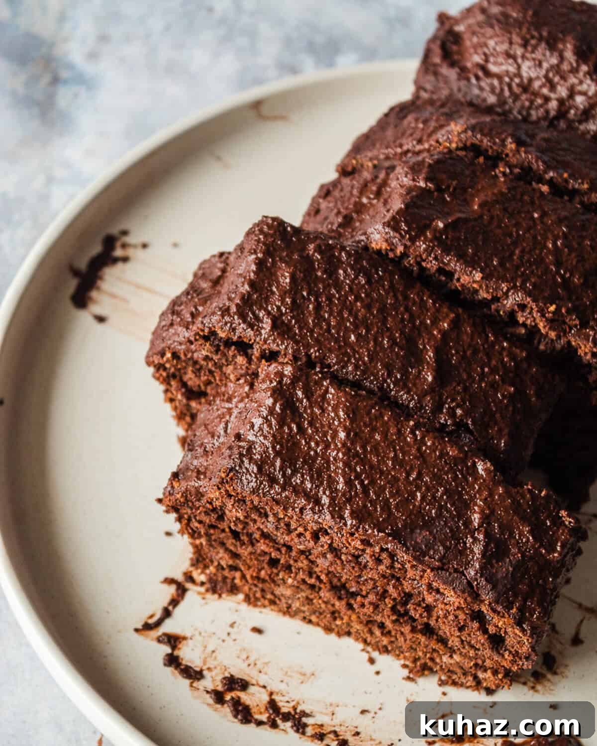 Avocado Chocolate Frosting Recipe — Creamy Dairy-Free 6 A sliced chocolate loaf cake on a white plate.