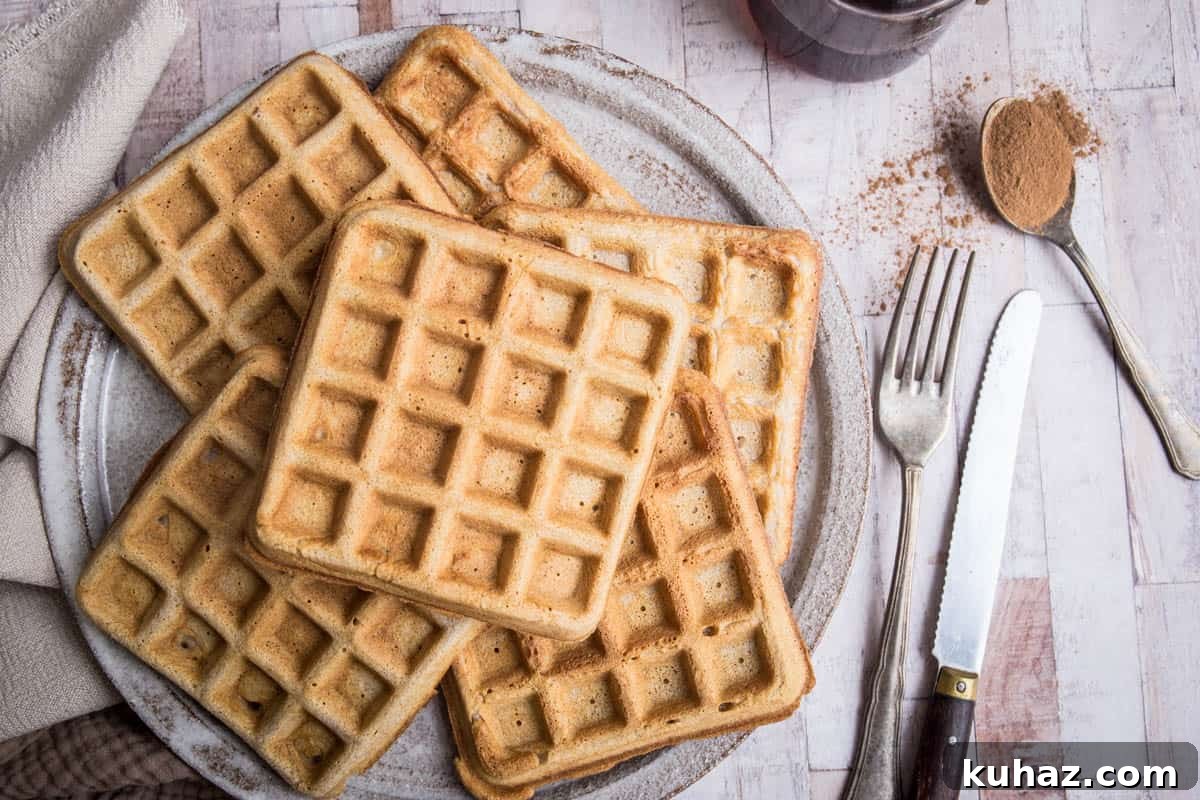 Gluten-Free Waffles: Quick, Crispy and Fluffy Recipe 3 Gluten-free waffles on a plate on a table next to cutlery and cinnamon