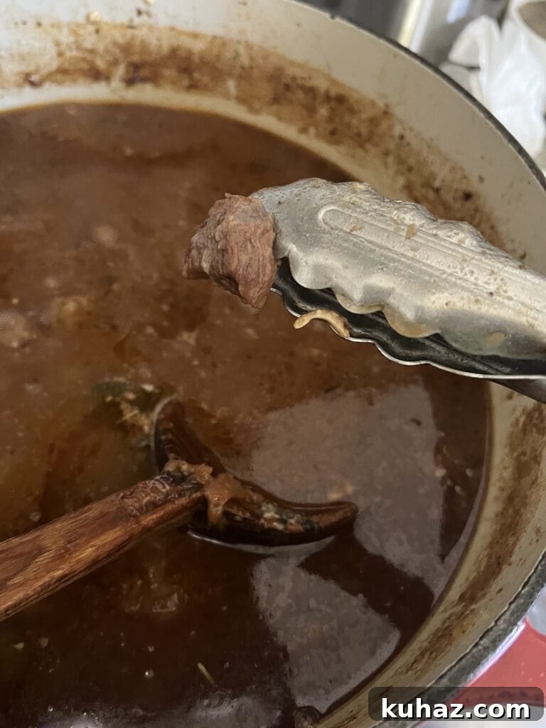 Italian Beef and Potato Soup - Nonna Pot-Roast 10 Checking tenderness/texture of piece of meat wit tongs.