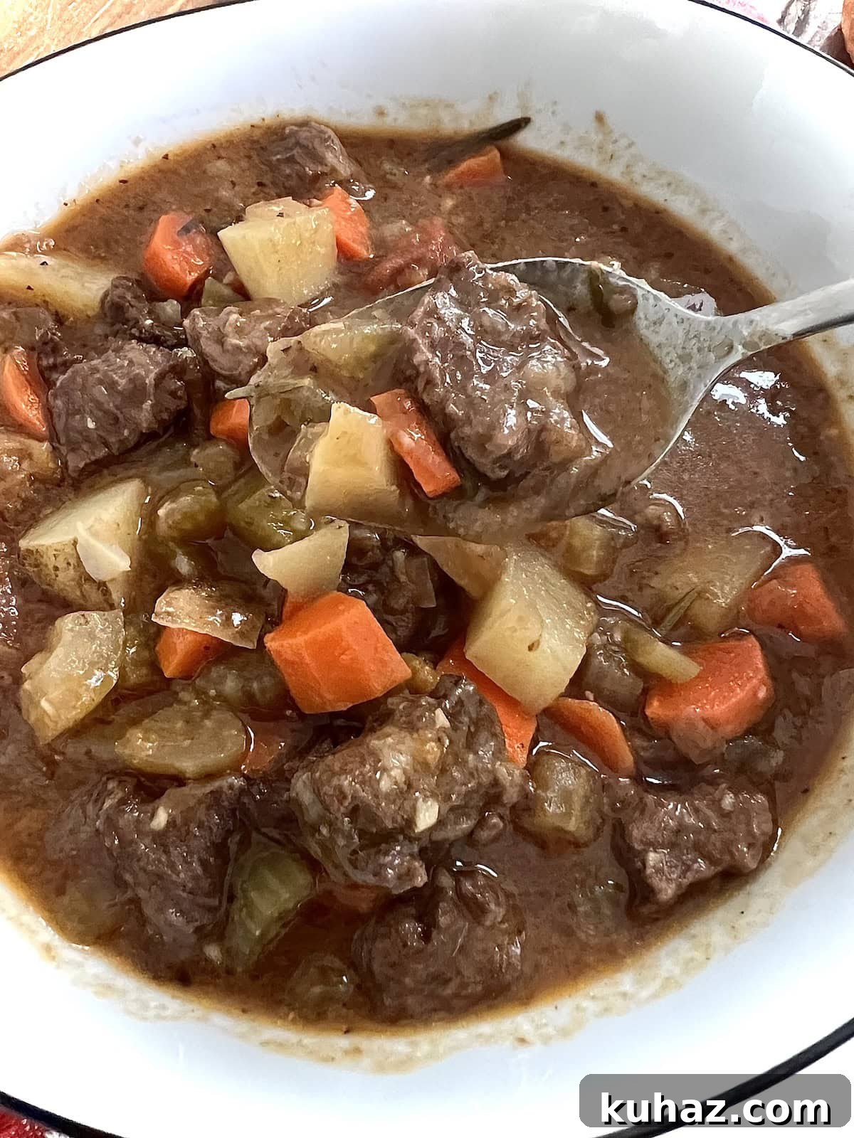 Italian Beef and Potato Soup - Nonna Pot-Roast 13 Close up of pieces of beef and potato soup on spoon ver bowl of soup.