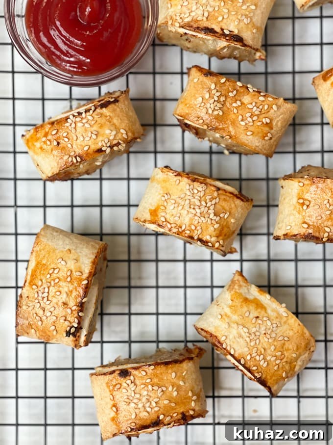 Crispy Chicken Sausage Rolls Recipe with Puff Pastry 8 the cooked sausage rolls on a cooling rack with a small bowl of tomato sauce
