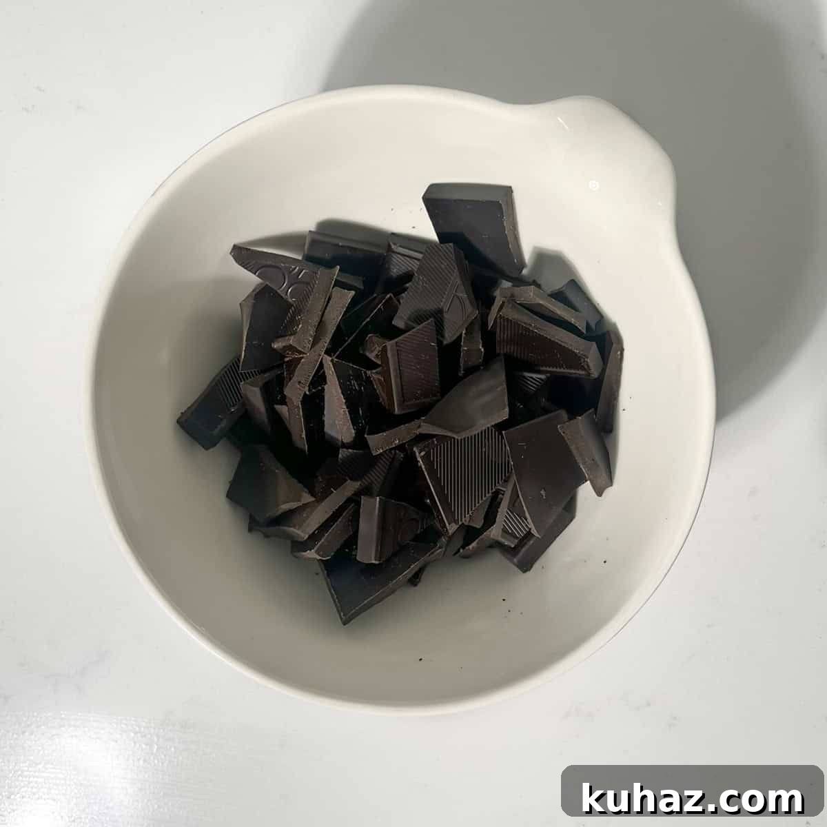 No-Churn Dark Chocolate Ice Cream Recipe 5 Broken up dark chocolate in a small white bowl.