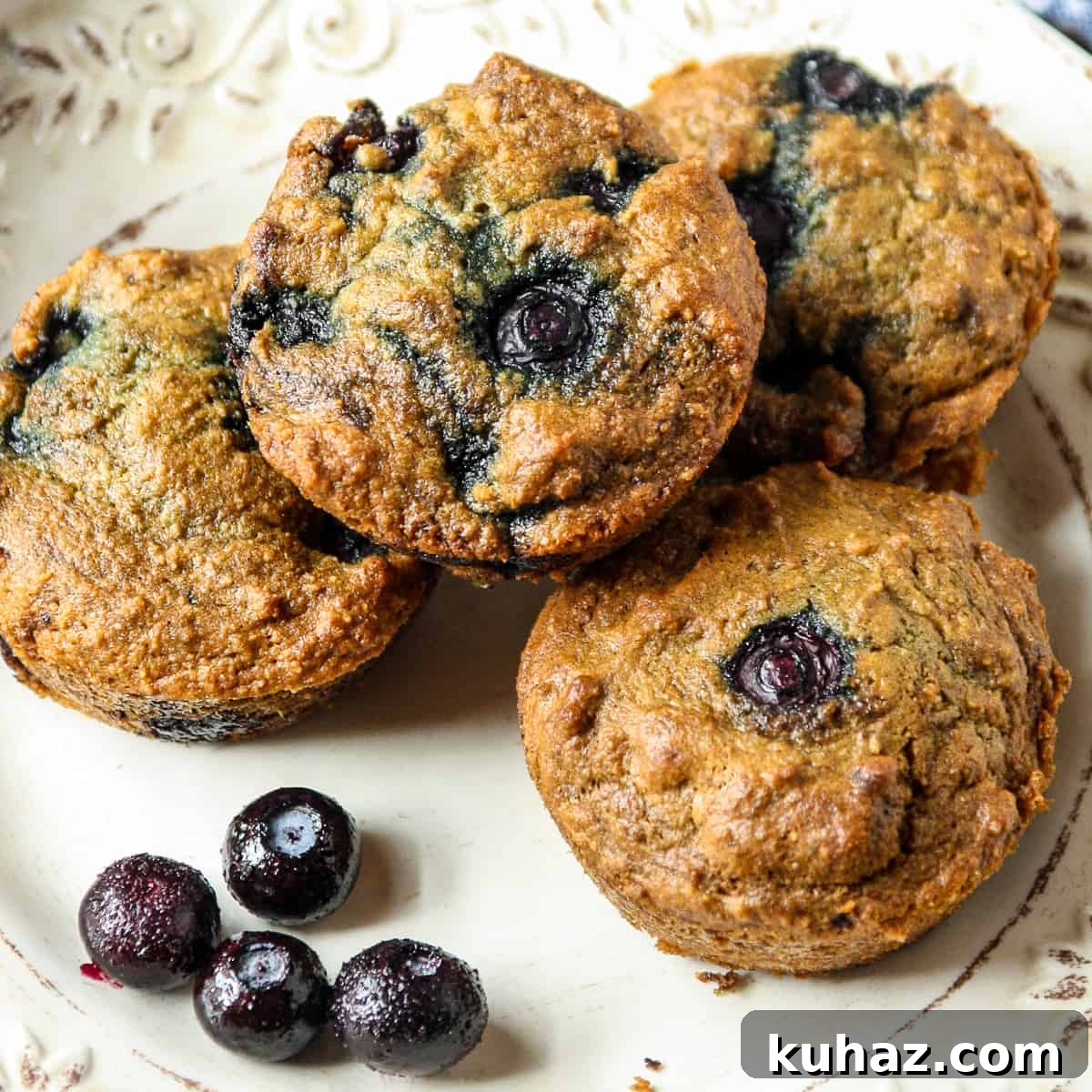 Almond Flour Blueberry Muffins, Tender and Fluffy 3 Almond flour blueberry muffins on a white plate.