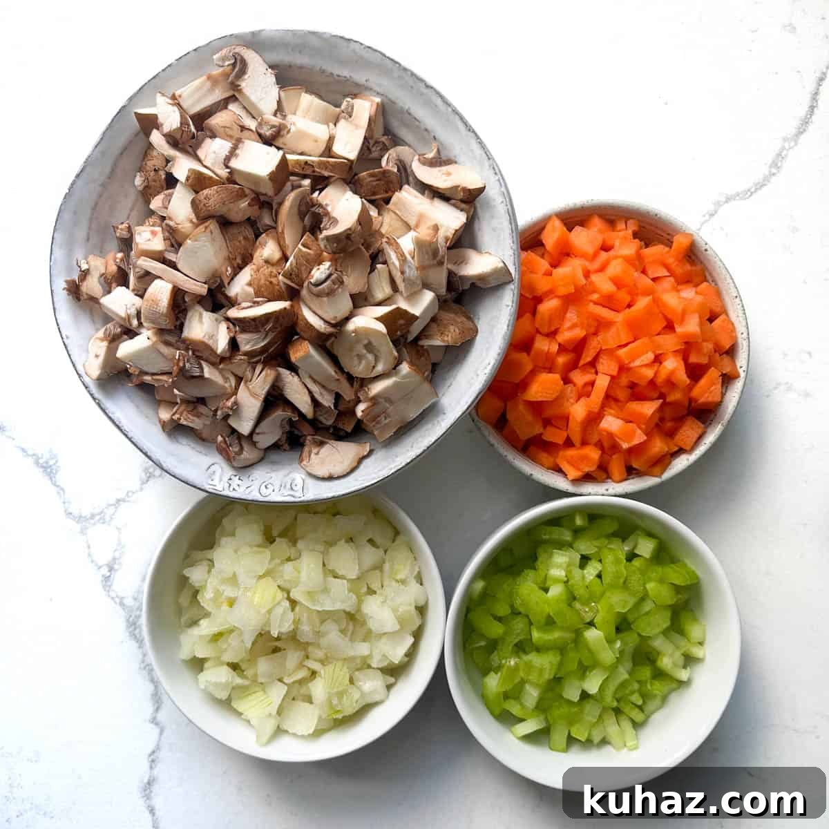 Chopped mushrooms, carrots, onions and celery in four whole bowls. 