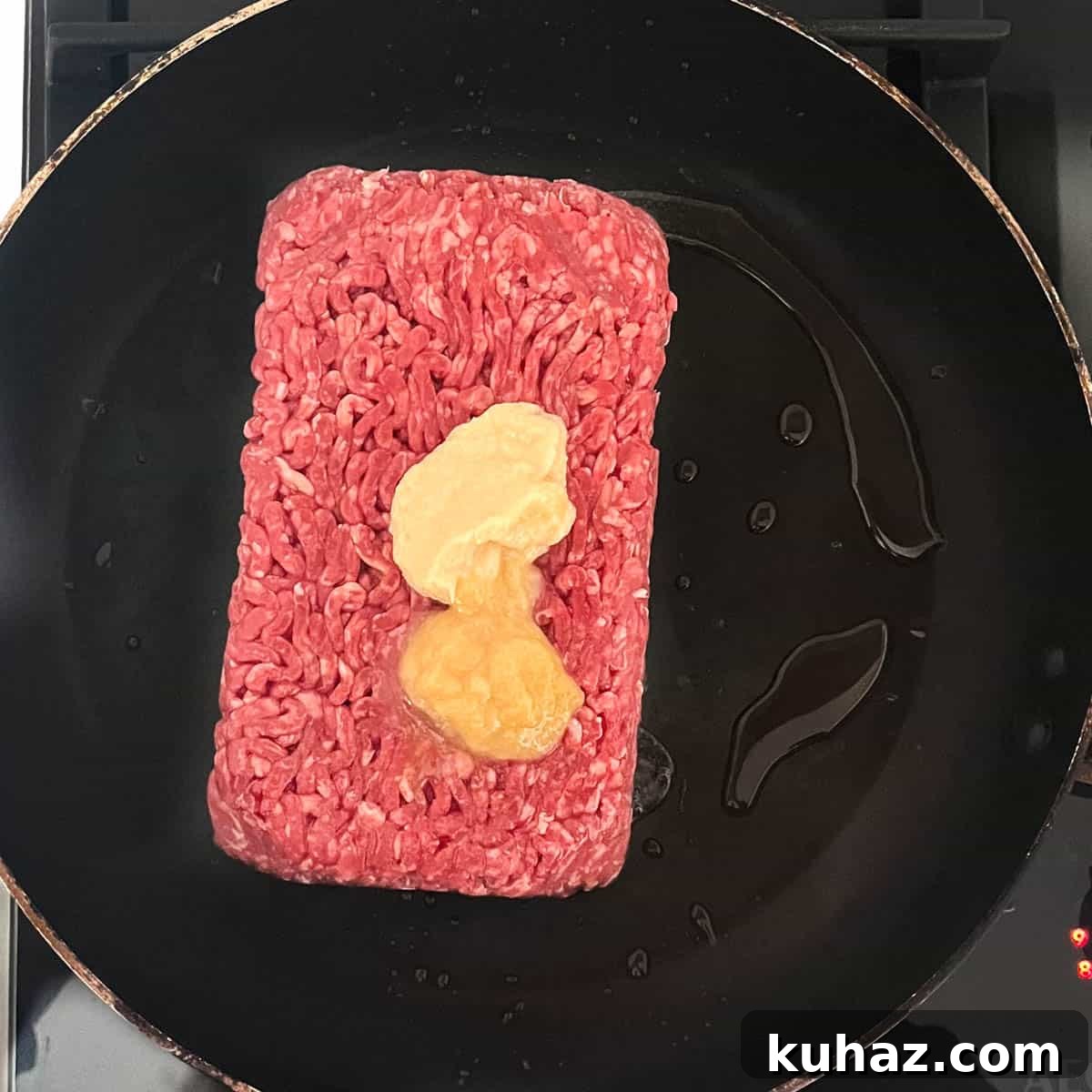 Adding beef mince, garlic and ginger to a large frying pan for the Yuk Sung.
