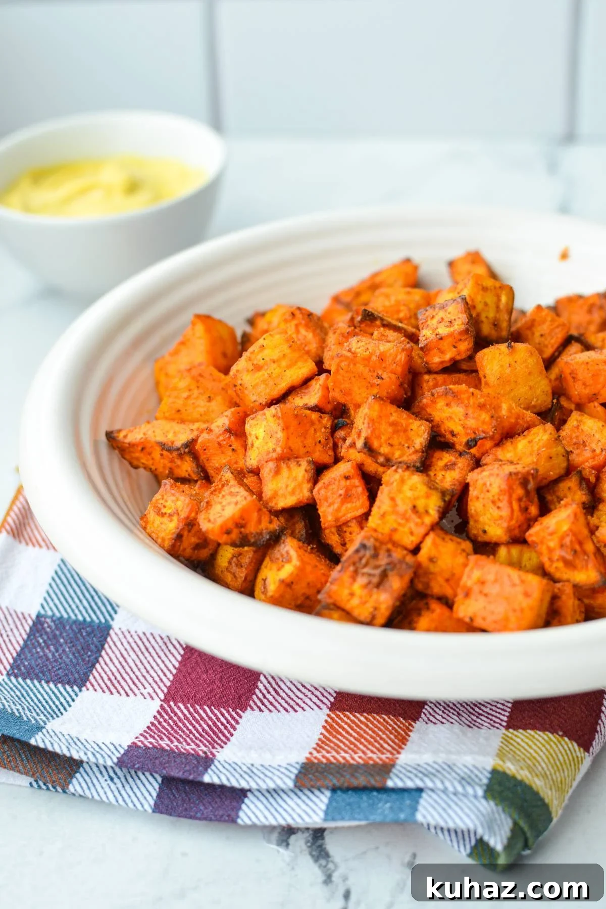 Crispy Air Fryer Sweet Potato Cubes 8 A bowl of roasted sweet potato cubes with a dipping sauce in the background.