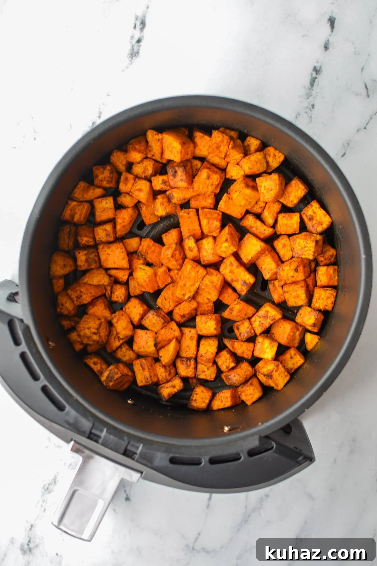 Crispy Air Fryer Sweet Potato Cubes 9 An air fryer basket with roasted sweet potato chunks.