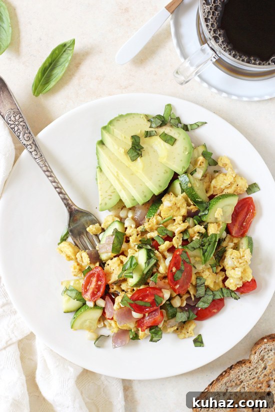 Overhead view of Summer Veggie Egg Scramble on a plate with a fork and a cup of coffee to the side.