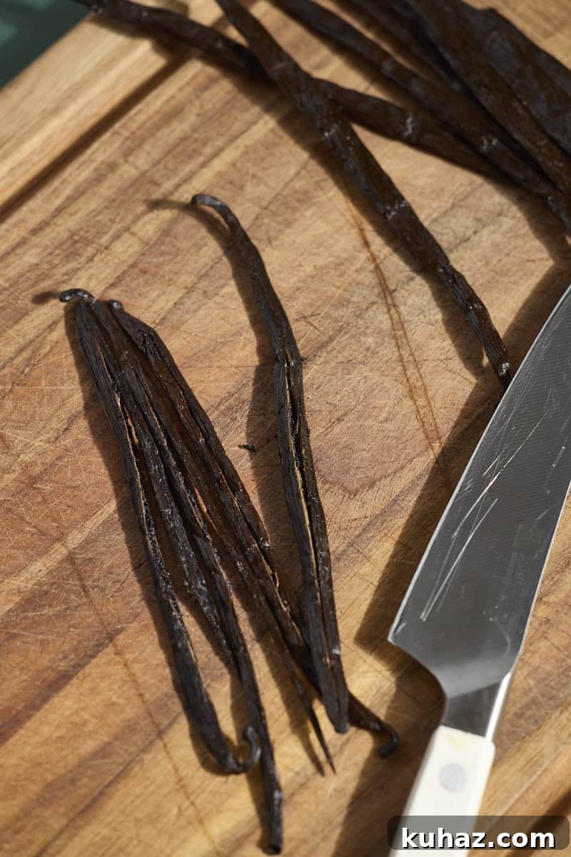 Vanilla beans cut in half on a wooden cutting board.
