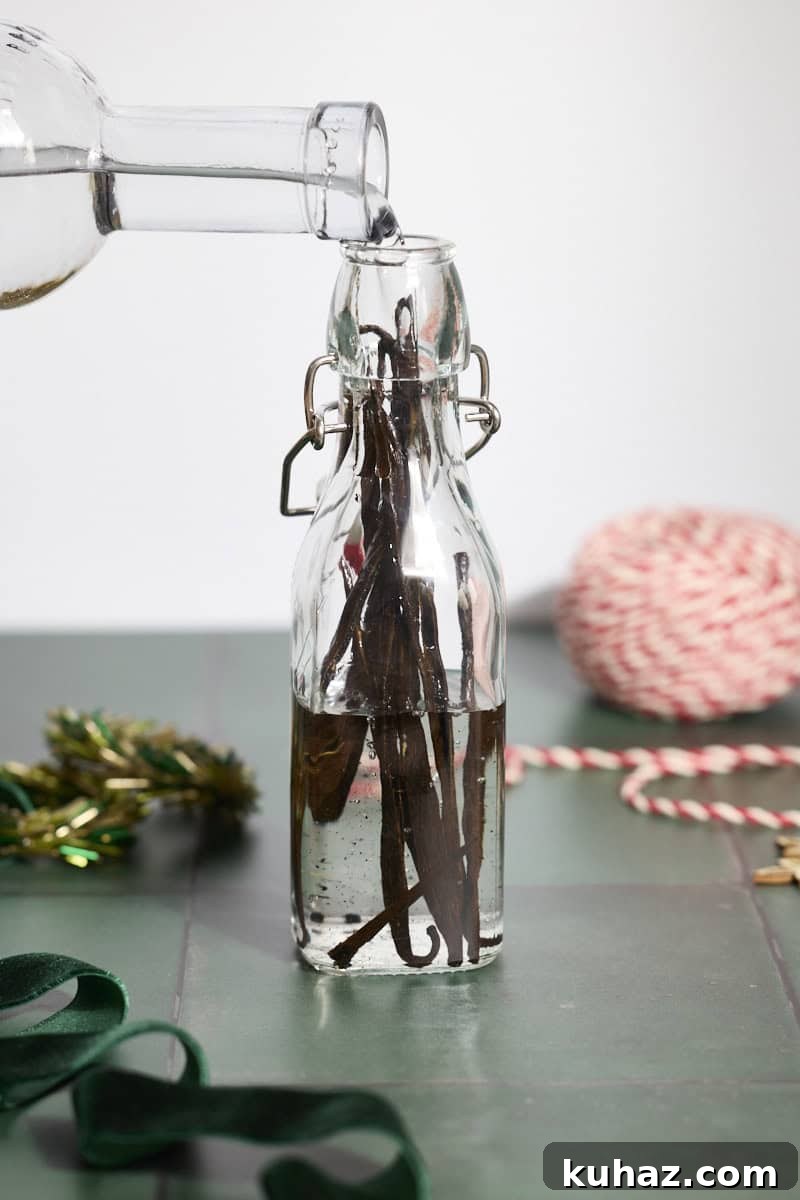 Vodka being poured into the bottle with vanilla beans.