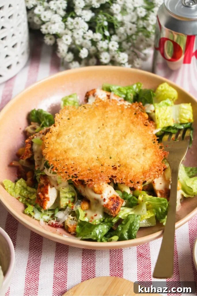 Parmesan crisp on top of caesar salad in a pink bowl.