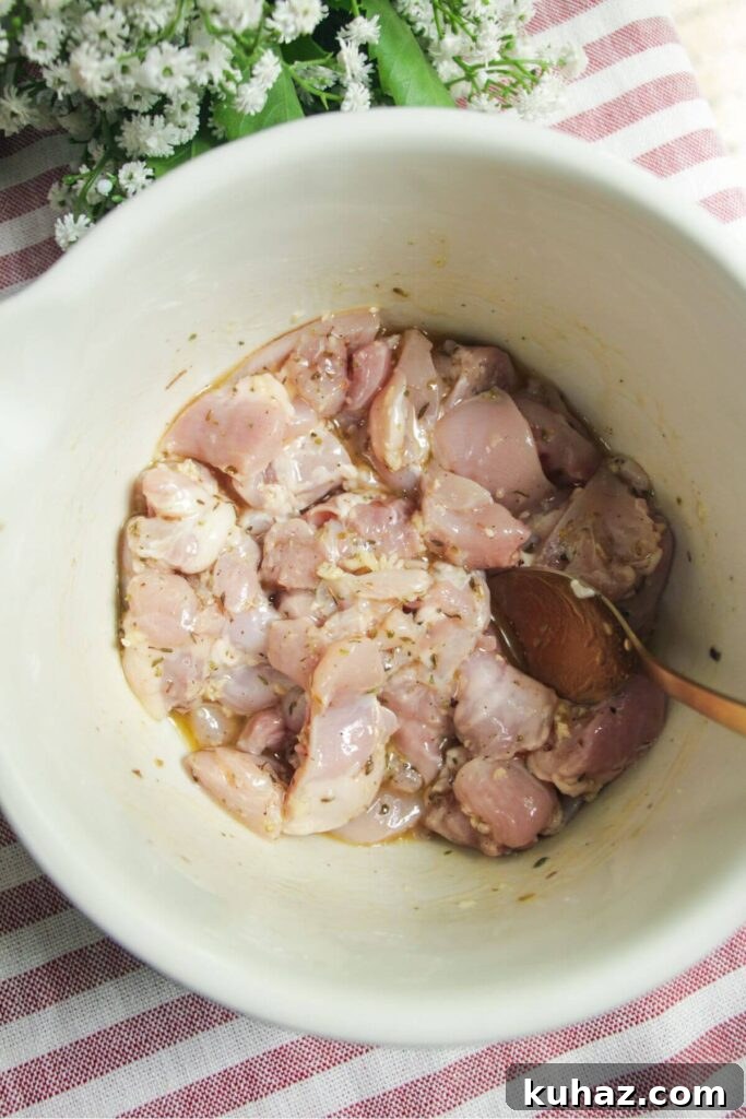 Diced chicken in a bowl with lemon juice, dried herbs and olive oil.