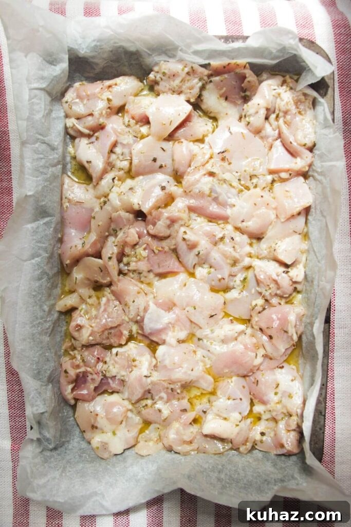 Marinated diced chicken laid out on a lined oven tray.