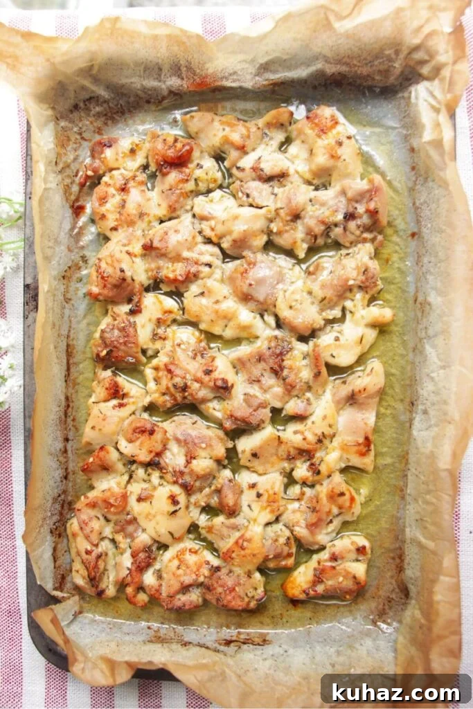 Charred cooked chicken in a lined oven tray.