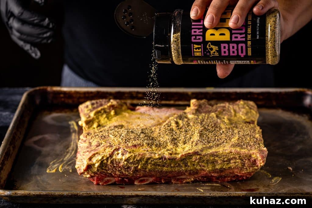 Smoked Beef Ribs Recipe: Fall-Off-the-Bone BBQ 4 Mustard-slathered beef ribs being sprinkled with beef rub.