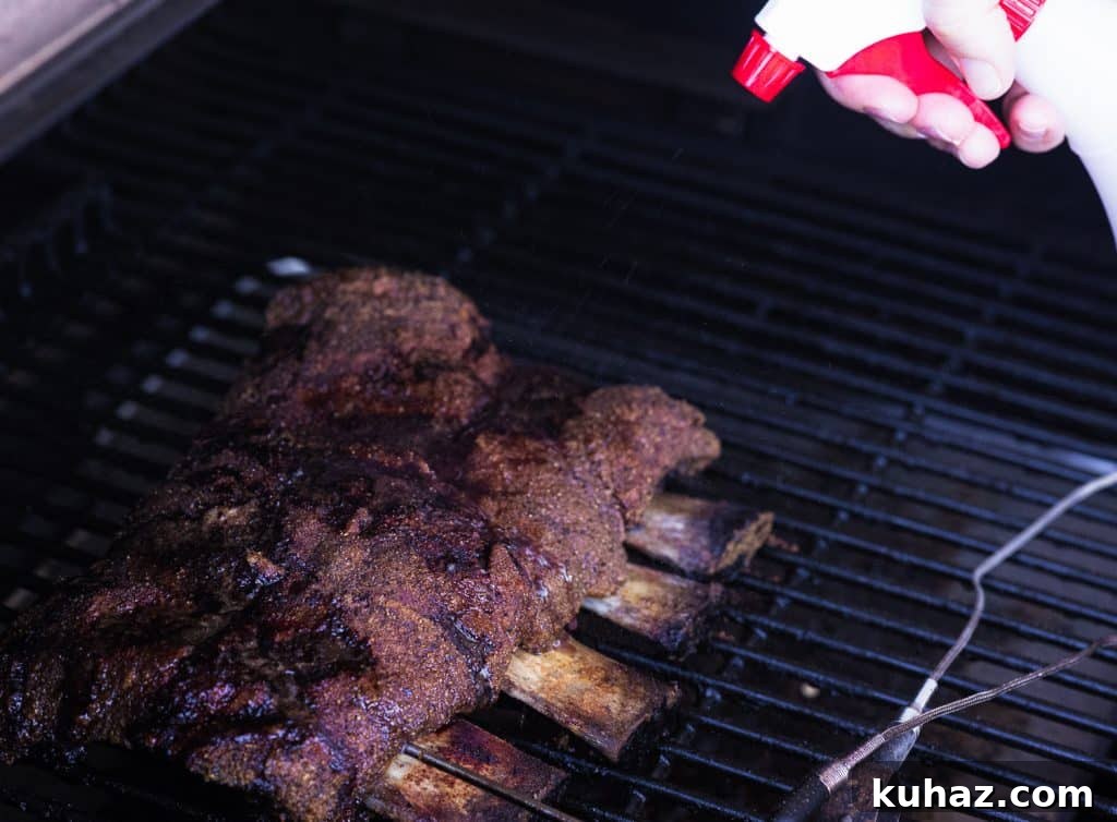 Smoked Beef Ribs Recipe: Fall-Off-the-Bone BBQ 5 Beef Ribs on the smoker being spritzed.