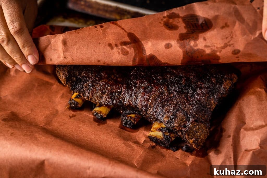 Smoked Beef Ribs Recipe: Fall-Off-the-Bone BBQ 6 Beef ribs being wrapped in peach butcher paper.
