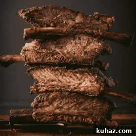 Stack of beef ribs on a wooden cutting board.