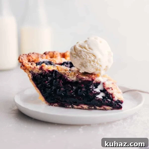Slice of berry pie with ice cream on top.