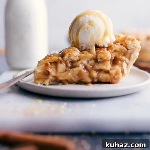 Slice of apple pie with ice cream and caramel sauce on top.