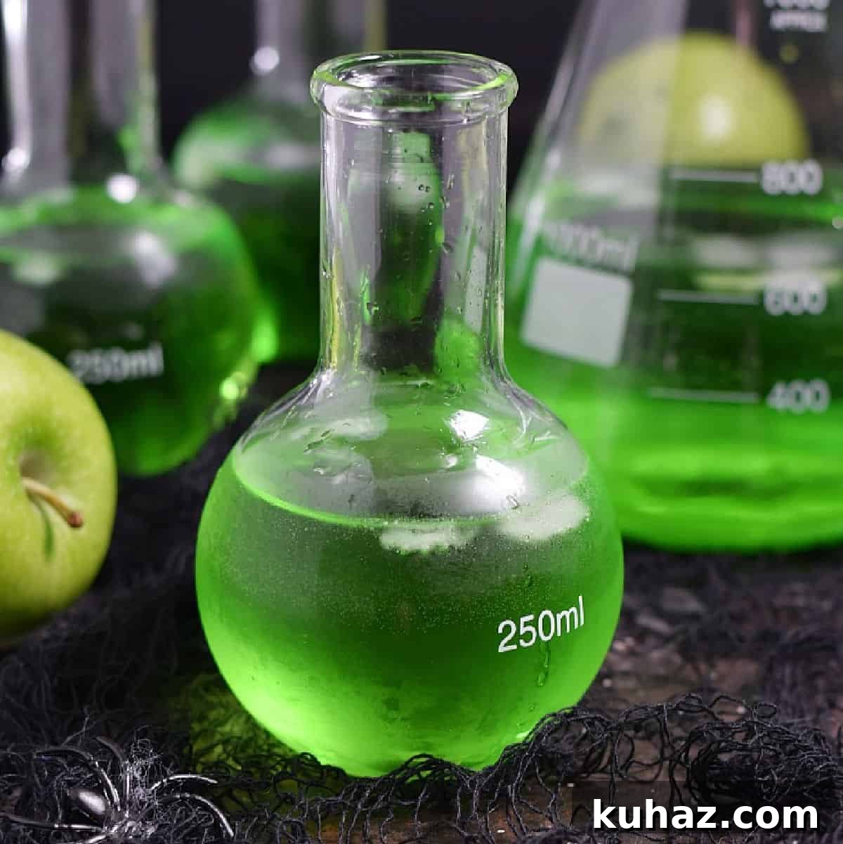 Poisoned apple cocktails in science bottles with green apples and a beaker.