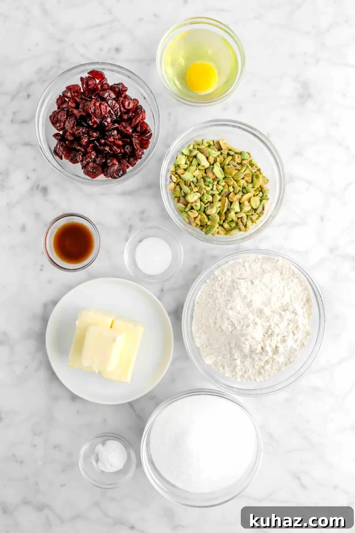 Cranberry Pistachio Slice-and-Bake Cookie Recipe 9 egg, dried cranberries, chopped pistachios, vanilla, salt, flour, butter, baking soda, and sugar on marble counter