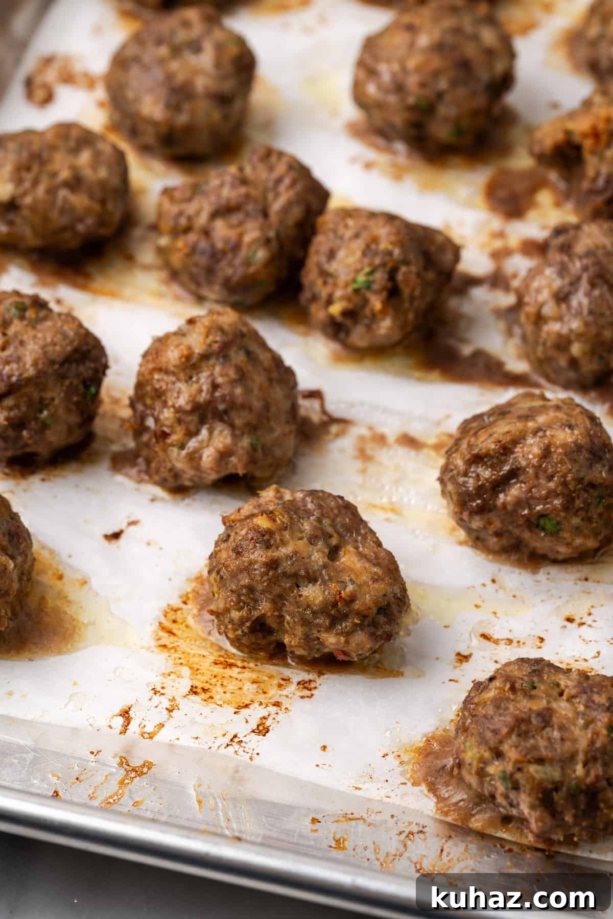 Baked gluten free meatballs on a baking sheet.