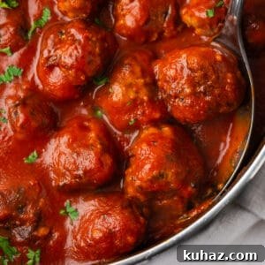 Gluten free meatballs in marinara sauce being served from a pan.