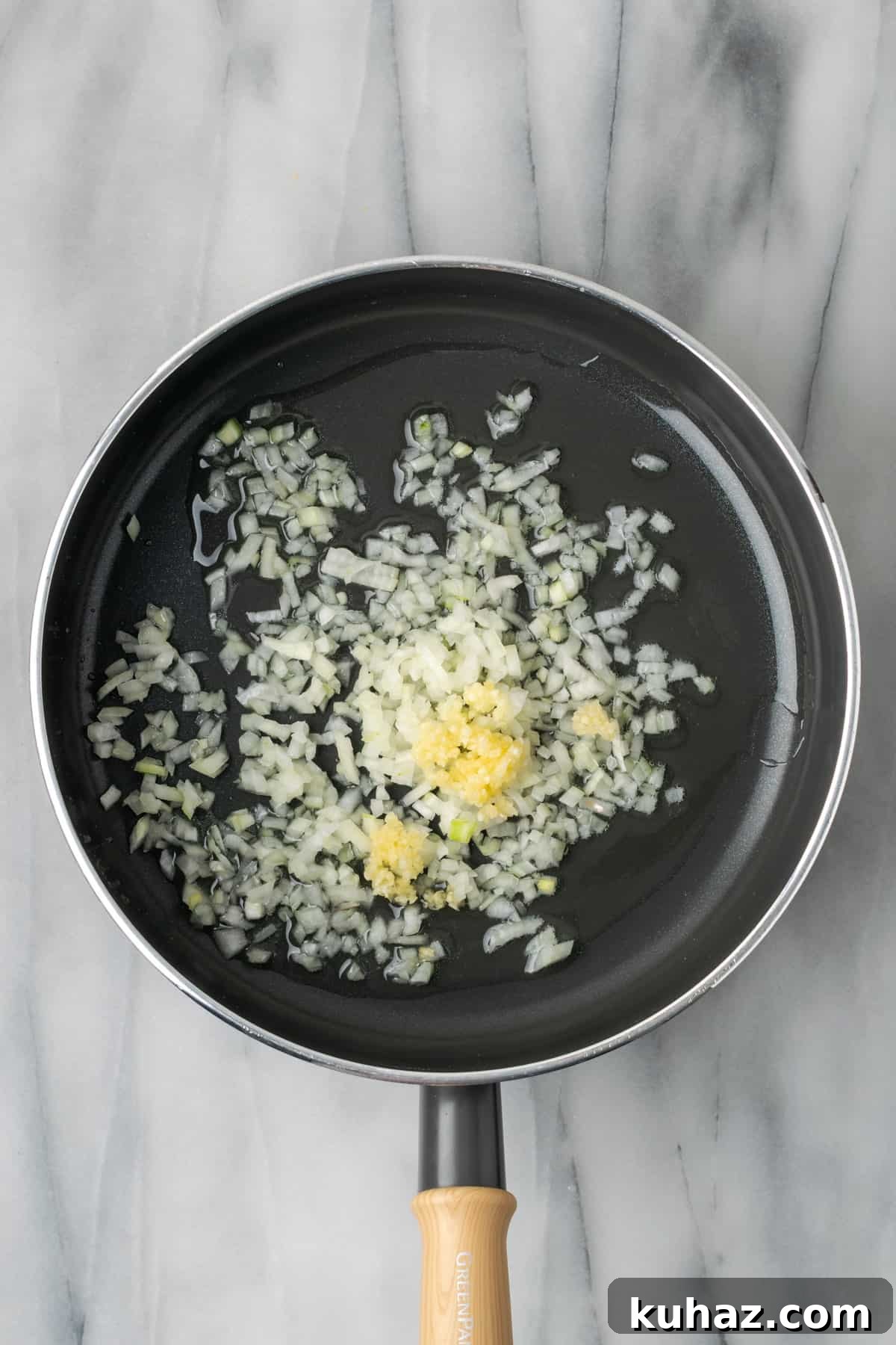 Onions and garlic being sauteed in a large saucepan.