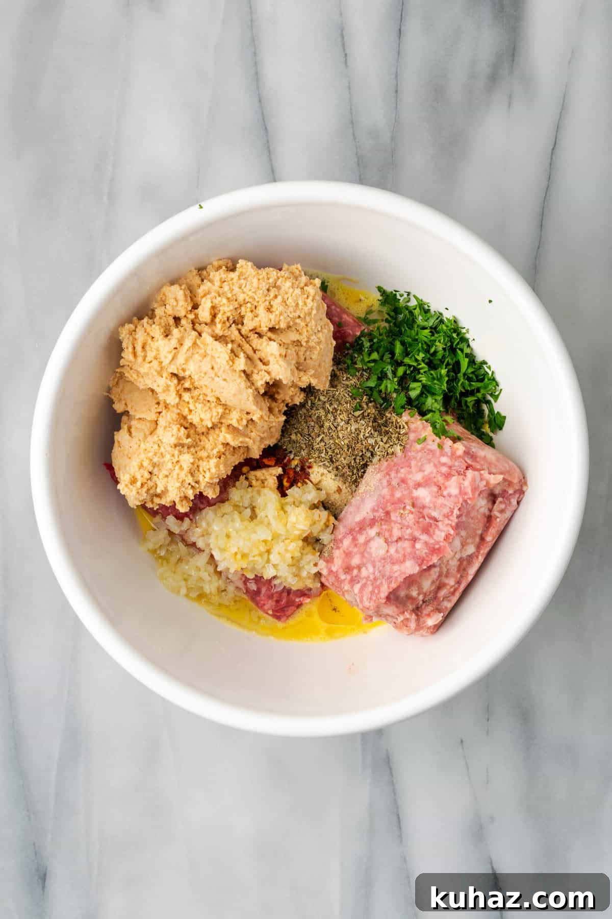 All of the gluten free meatball ingredients combined together in a large mixing bowl.