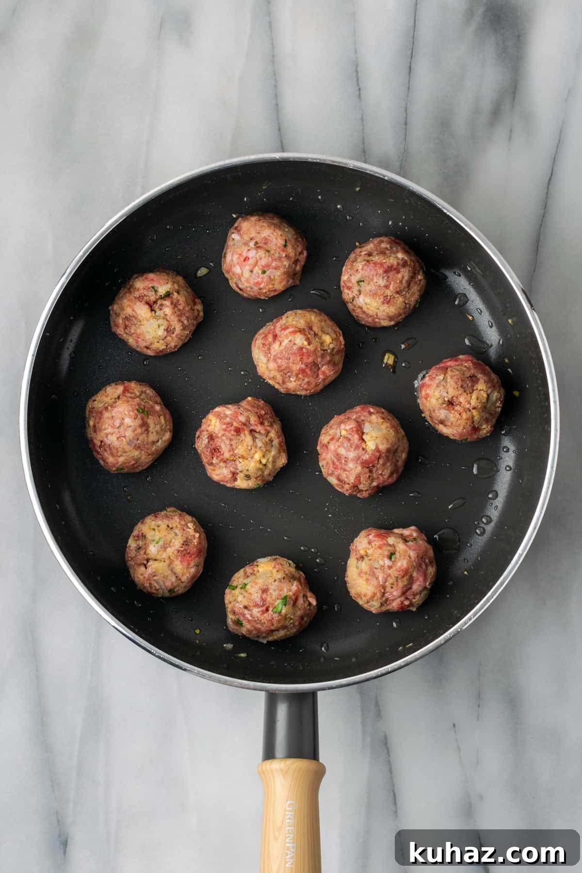 Raw meatballs cooking in a large saucepan. 